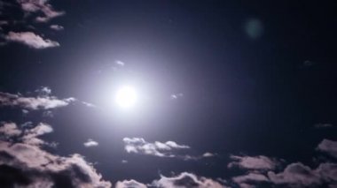 Dolunay, karanlık bulutların arasından gece gökyüzünde hareket eder, Timelapse. Mistik parlak ay bulutların arka planına doğru yükseliyor. Ay ışığı karanlık gece gökyüzünde parlar. Zaman aşımı. 4K