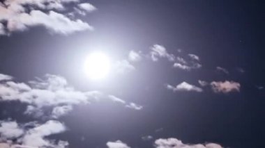 Full moon moves in the night sky through dark clouds, Timelapse. The mystical bright moon rises up against the background of clouds. Moonlight shines in the black night sky. Time lapse.