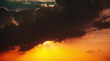 Dramatic sunset with sun rays in the Sky through orange layered clouds, Timelapse. The big bright orange sun with sun rays moves down over the horizon. Awesome epic cloud space. Time Lapse. Sundown