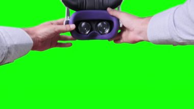 Point of view young man putting on VR Headset on green screen. POV of taking on VR glasses virtual reality. Young male hands hold virtual reality helmet. Close-up. Using VR Mask. Alpha channel, 4K
