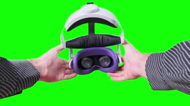 POV elemanı yeşil ekranda VR kulaklığı takıyor. Sanal gerçeklik gözlüğü takmak. Genç erkek eller sanal gerçeklik kaskını tutuyor. Meta-evrene daldırma, artırılmış gerçeklik, meta-evrene batırma