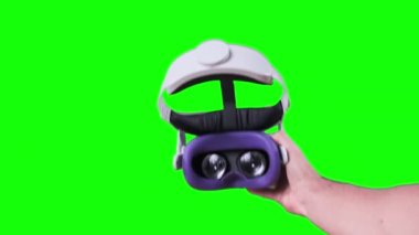 POV adamı yeşil ekranda sanal gerçeklik kaskını takıyor. Sanal gerçeklik gözlüğü takmak. Genç erkek eller VR kulaklığı tutuyor. Meta-evrene daldırma, artırılmış gerçeklik, meta-evrene batırma