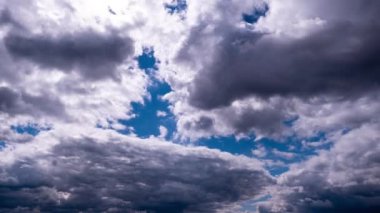Kümülüs bulutlarının mavi gökyüzünde hareket etme zamanı. Karanlık ve aydınlık bulutların şekil değiştirdiği dramatik bulutlu bir alan. Atmosfer arkaplanı, zaman atlaması. Hava değişikliği. Doğa, Gökyüzü bulutları. 4K