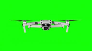 Drone hovering in the air on a green screen. Real quadcopter with camera flights on transparent background. Isolated portable copter on alpha matte. Aircraft blades rotate in hanging. Alpha channel 4K