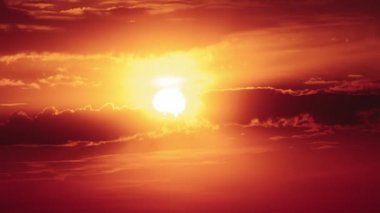 Dramatic sunset with sun rays in the Sky through orange layered clouds, Timelapse. Awesome epic cloud space. The big bright orange sun moves down over the horizon. Time Lapse. Amazing vibrant sundown
