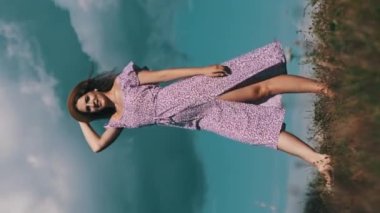 Dikey, açık tenli, mor elbiseli, hasır şapkalı, yeşil çayırda yürüyen, kıvrılan, ağır çekimde güzel bir kadın. Gökyüzüne karşı gülümseyen ve kameraya bakan çekici bir kızın portresi. Yaz yaşam tarzı