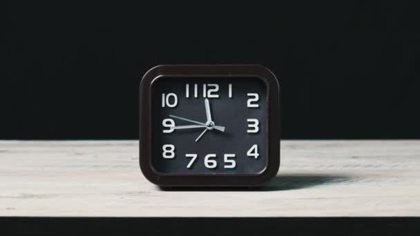 木制桌子上的模拟时钟和黑色背景显示时间 二手移动的圆形棕色拨号盘的方形机械手表的特写 时间管理 日常事务 — 图库视频影像