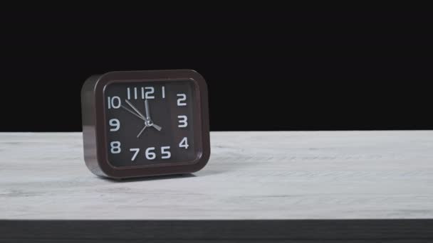 木制桌子上的指针时钟和黑色背景显示时间为12点 二手移动沿着圆形拨号盘的特写 箭头褐色钟形正方形特写 时间管理 时间表 — 图库视频影像