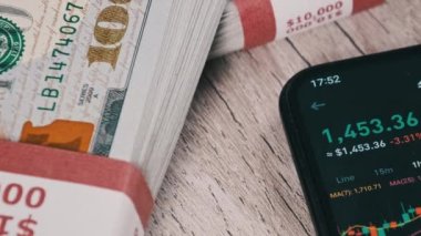 Akıllı telefon ekranındaki şifreli para birimi fiyatları dolarlarla dolu bir masada. Dijital pazarın yanındaki bir telefon uygulamasında şifreli ticaret kavramı. Şifreli geleceğe yatırım. Ethereum 'un Kripto varlık fiyat tablosu