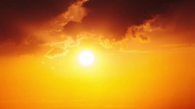 Dramatic sunset with sun rays in the Sky through orange layered clouds, Timelapse. The big bright orange sun with sun rays moves down over the horizon. Awesome epic cloud space. Time Lapse. Sundown