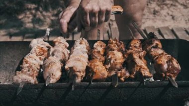 Doğadaki ızgarada şiş ızgarada barbekü yapmak. Terbiye edilmiş kebap mangal kömüründe kızartılır. Güneşli bir günde sahilde barbekü pişirme işlemi. BBC 'deki metal şişte lezzetli yemekler. Şişler açık
