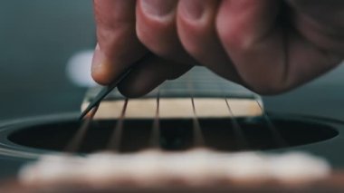 Yavaş çekimde akustik gitarda titreşimli metalik teller. Slow Movement 240 fps, yakın çekim gitar destesi. Klasik gitar telleri arabulucuya dokunurken titreşir. Gitarist bronz tellere dokundu