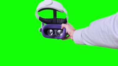 POV elemanı yeşil ekranda VR kulaklığı takıyor. Sanal gerçeklik gözlüğü takmak. Genç erkek eller sanal gerçeklik kaskını tutuyor. Meta-evrene daldırma, artırılmış gerçeklik, meta-evrene batırma