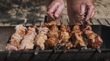 Process of cooking delicious shish kebab on metal skewer in summer outdoors. Grilling shashlik on barbecue grill. Marinated kebab is grilled on charcoal. Skewers on skewers. Weekend picnic Street food