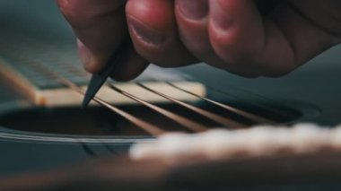Yavaş çekimde akustik gitarda titreşimli metalik teller. Slow Movement 240 fps, yakın çekim gitar destesi. Klasik gitar telleri arabulucuya dokunurken titreşir. Gitarist bronz tellere dokundu