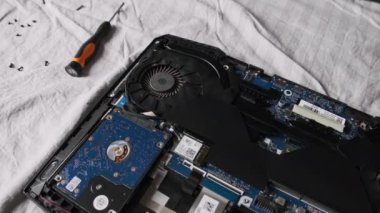 Laptop tamiri. Parçalanmış dizüstü bilgisayar radyo şefinin masasında yatıyor. Ana kart, soğutma vantilatörleri ve radyo parçaları bir dizüstü bilgisayarın içinde. Bilgisayar ekipmanlarının bakımı. Bilgisayar onarım servisi