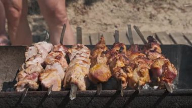 Grilling shashlik on barbecue grill outdoors. Process of cooking delicious shish kebab on a metal skewer in summer. Roast beef on BBQ. Marinated kebab grilled on charcoal. Weekend picnic. Street food