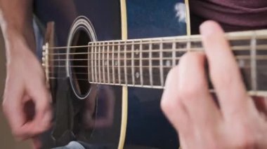 Gitarist evde akustik gitar çalar. Adam perdeleri tıngırdatır ve şarkıyı çalar. Klasik gitar çalmayı öğreniyorum. Genç müzisyen evdeki oturma odasında gitar çalıyor..