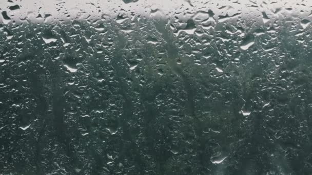 窓の上に雨が降った 窓の外で雨 秋のブルース 雨の天気曇りの日 雨が窓ガラスに降り クローズアップ 雨の滴がガラスの下を走る 秋の抽象的背景 — ストック動画