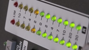 Vertical video LED indicator of sound level signal on mixing console. LED strip in green and yellow on output level indicator. Volume level changes of indicator lights. VU meters on sound desk. Macro