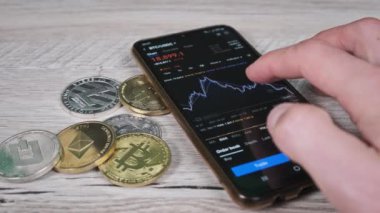 Yatırımcı akıllı telefon ekranındaki kripto para birimini kontrol ediyor. Şifreli paralarla telefon ekranında kripto ticareti. İşadamı, dijital borsa yatırımlarını inceliyor. Bitcoin fiyatı BTC Pazarı