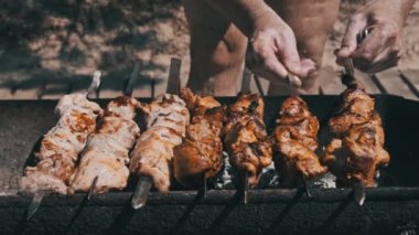 Process of cooking delicious shish kebab on metal skewer in summer outdoors. Grilling shashlik on barbecue grill. Marinated kebab is grilled on charcoal. Skewers on skewers. Weekend picnic Street food