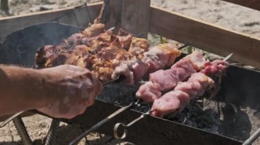 Process of cooking delicious shish kebab on metal skewer in summer outdoors. Grilling shashlik on barbecue grill. Marinated kebab is grilled on charcoal. Skewers on skewers. Weekend picnic Street food