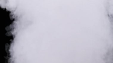 Gerçekçi duman veya buhar bulutları yavaş çekimde yükselir, kompozit ve video düzenleme için kullanılır. Özel efekt, doku. Siyah arka planda duman bulutu var. Buharın soyut parçacıkları