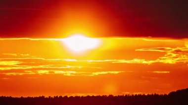 Dramatic sunset with sun rays in the Sky through orange layered clouds, Timelapse. The big bright orange sun with sun rays moves down over the horizon. Awesome epic cloud space. Time Lapse. Sundown