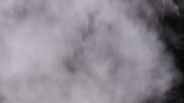 Siyah arka planda beyaz duman. Bir buhar bulutu yükseliyor. Yüzen sis. Buhar buharı patlaması. Şeffaf duman bulutları, soyut sis, buhar dokusu. Gerçek atmosferik etki. 4K.