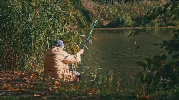 Pescador Idoso Solitário Sentado Margem Rio Com Uma Vara Pesca — Vídeo de Stock