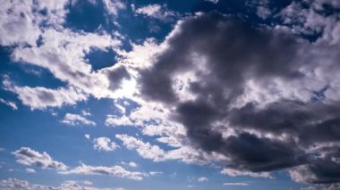 Mavi gökyüzünde, parlak güneşin altında hareket eden bulutlar, zaman kavramı. Bulut uzayı arka planı. Muhteşem cennette hafif kabarık bulutların zamanı. Manzaralı atmosfer. Hava değişikliği. Doğa. 4K