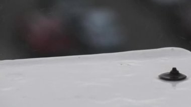 Yağmur damlaları pencerenin kenarına yavaş çekimde düşer, yakın planda. Yağmurlu bir günde yağmur damlaları çıkıntıya çarpar. Sonbahar fırtınası sırasında pencere pervazı. Su damlaları düşer. Sonbahar melankolisi.