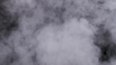 Gerçekçi duman veya buhar bulutları yavaş çekimde yükselir, kompozit ve video düzenleme için kullanılır. Özel efekt, doku. Siyah arka planda duman bulutu var. Buharın soyut parçacıkları