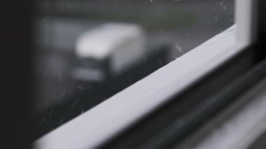 Yağmur damlaları pencerenin kenarına ağır çekimde vuruyor. Yağmurlu bir günde yağmur damlaları pencere kenarına düşer, ağır çekimde. Fırtına sırasında pencere pervazı, yakın çekim. Gri bir havayla sonbahar yağmuru. Sonbahar melankolisi