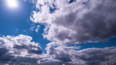 Mavi gökyüzünde, parlak güneşin altında hareket eden bulutlar, zaman kavramı. Bulut uzayı arka planı. Muhteşem cennette hafif kabarık bulutların zamanı. Manzaralı atmosfer. Hava değişikliği. Doğa. 4K