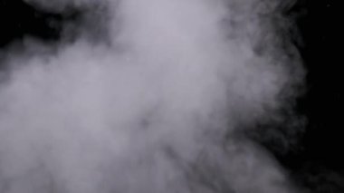 Gerçekçi duman veya buhar bulutları yavaş çekimde yükselir, kompozit ve video düzenleme için kullanılır. Özel efekt, doku. Siyah arka planda duman bulutu var. Buharın soyut parçacıkları