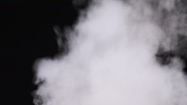 Gerçekçi duman veya buhar bulutları yükselir, kompozit ve video düzenleme için kullanılır. Özel efekt, doku, görüntü. Siyah arka planda duman bulutu var. Buhar dokusunun soyut parçacıkları. 4K