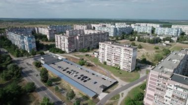 Şehrin yerleşim bölgesindeki yeşil bir ormanın yakınındaki çok katlı binalar. Çatılar ve cepheler. Yüksek katlı apartman blokları. İHA panorama SSCB renkli binalar ve gökyüzü.
