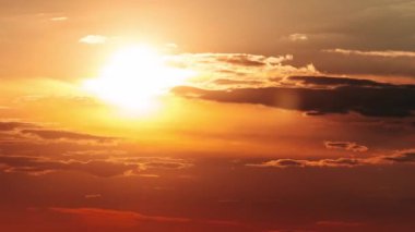 Timelapse of dramatic sunset with sun rays in the Sky through orange layered clouds. The big bright orange sun with sun rays moves down over the horizon. Awesome epic cloud space. Time Lapse. Sundown