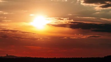 Dramatic sunset with sun rays in the Sky through orange layered clouds, Timelapse. The big bright orange sun with sun rays moves down over the horizon. Awesome epic cloud space. Time Lapse. Sundown