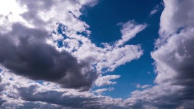 Mavi gökyüzünde, parlak güneşin altında hareket eden bulutlar, zaman kavramı. Bulut uzayı arka planı. Muhteşem cennette hafif kabarık bulutların zamanı. Manzaralı atmosfer. Hava değişikliği. Doğa. 4K