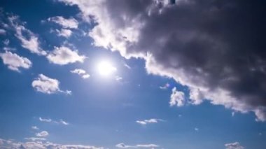 Mavi gökyüzünde, parlak güneşin altında hareket eden bulutlar, zaman kavramı. Bulut uzayı arka planı. Muhteşem cennette hafif kabarık bulutların zamanı. Manzaralı atmosfer. Hava değişikliği. Doğa. 4K