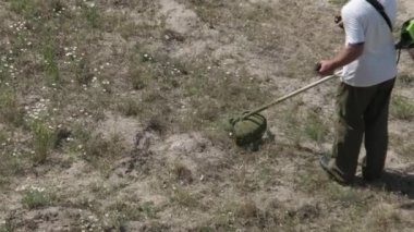 Adam çimleri manuel benzin çim biçme makinesiyle biçiyor. Bahçıvan çim biçme makinesi yeşil çim biçiyor. Bahçe bakımı aletleri. Çim biçme makinesiyle çim biçme işlemi. Yaz, güneşli gün.
