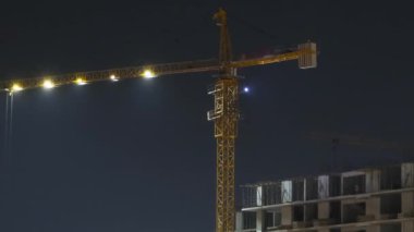 Gece Bina İnşaatı. Zaman ayarlı. İnşaat sahasında Aydınlatma yapan Turna Kulesi şehirde Modern Gökdelen inşa ediyor. 24 saat inşaatta. Çok katlı bir ev inşa ediliyor.