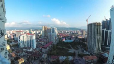Bir inşaat alanı, gökdelenler, evler, trafik ve dağlarla birlikte Batumi şehrindeki Kentsel Alanın Zamanı. Bulutlar gün batımında şehrin üzerinde hareket eder. Yukarıdan panoramik görünüm.