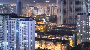 Şehirde geceleri değişen pencere ışıklarıyla çok katlı binalar. Zaman ayarlı. Gökdelenler ve inşaat alanlarıyla birlikte City Space 'in zaman atlaması. Pencerelerdeki ışık açılıp kapanıyor. Batum
