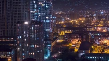 Multistorey Buildings with Changing Window Lighting At Night in City. Timelapse. Time lapse of City Space with Modern Skyscrapers, slums, and Construction Site. The light in the windows is turned on