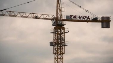 Tower Crane Bulutların Arkaplanındaki İnşaat Alanında Yüksek Binada Yükleme Yapıyor. Zaman ayarlı. Turna kulübesi. Bina İnşaat. Gökdelen inşa etme süreci. Batumi, Georgia. Süre