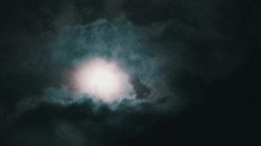 Gece gökyüzündeki dolunay kara bulutların arasında hareket eder, Timelapse. Mistik parlak ay bulutların arka planına doğru yükseliyor. Ay ışığı karanlık gece gökyüzünde parlar. Zaman aşımı. 4K